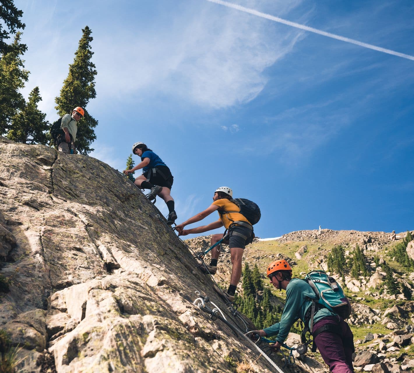 Three people climbing on the Via Ferrata at Taos Ski Valley.