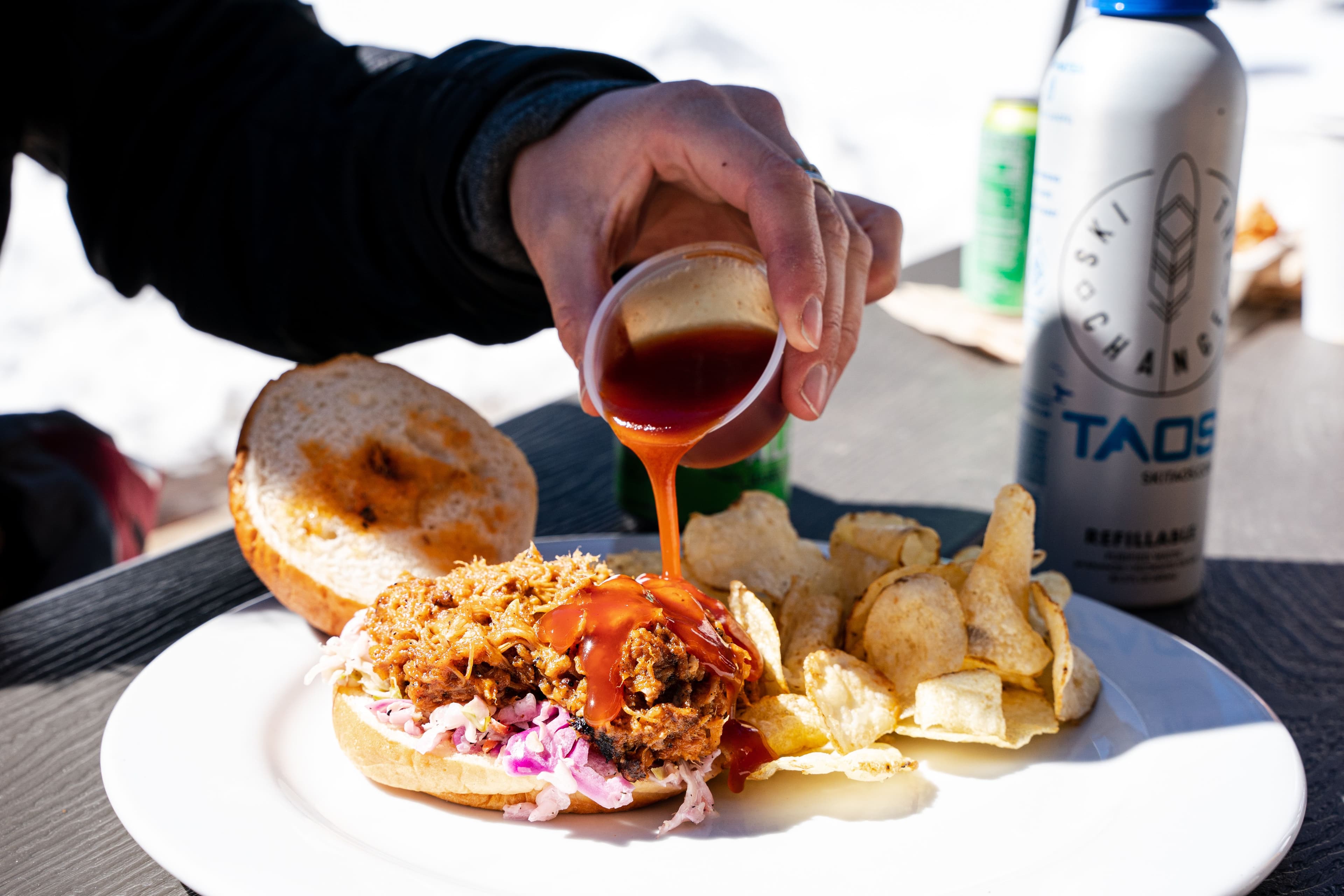 A pulled pork sandwich being slathered in BBQ sauce at Phoenix Barbecue.