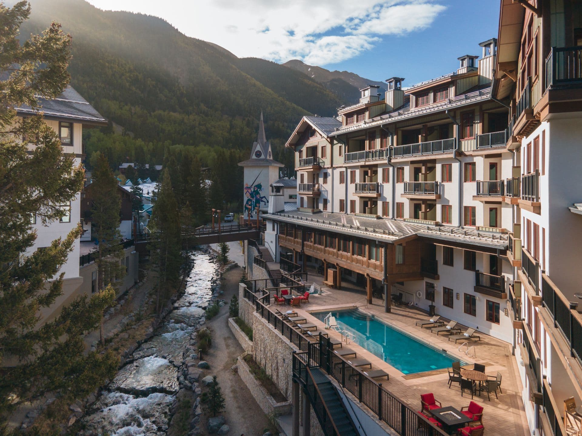 Exterior of The Blake and its pool as the sun rises over Taos Ski Valley in the summertime.