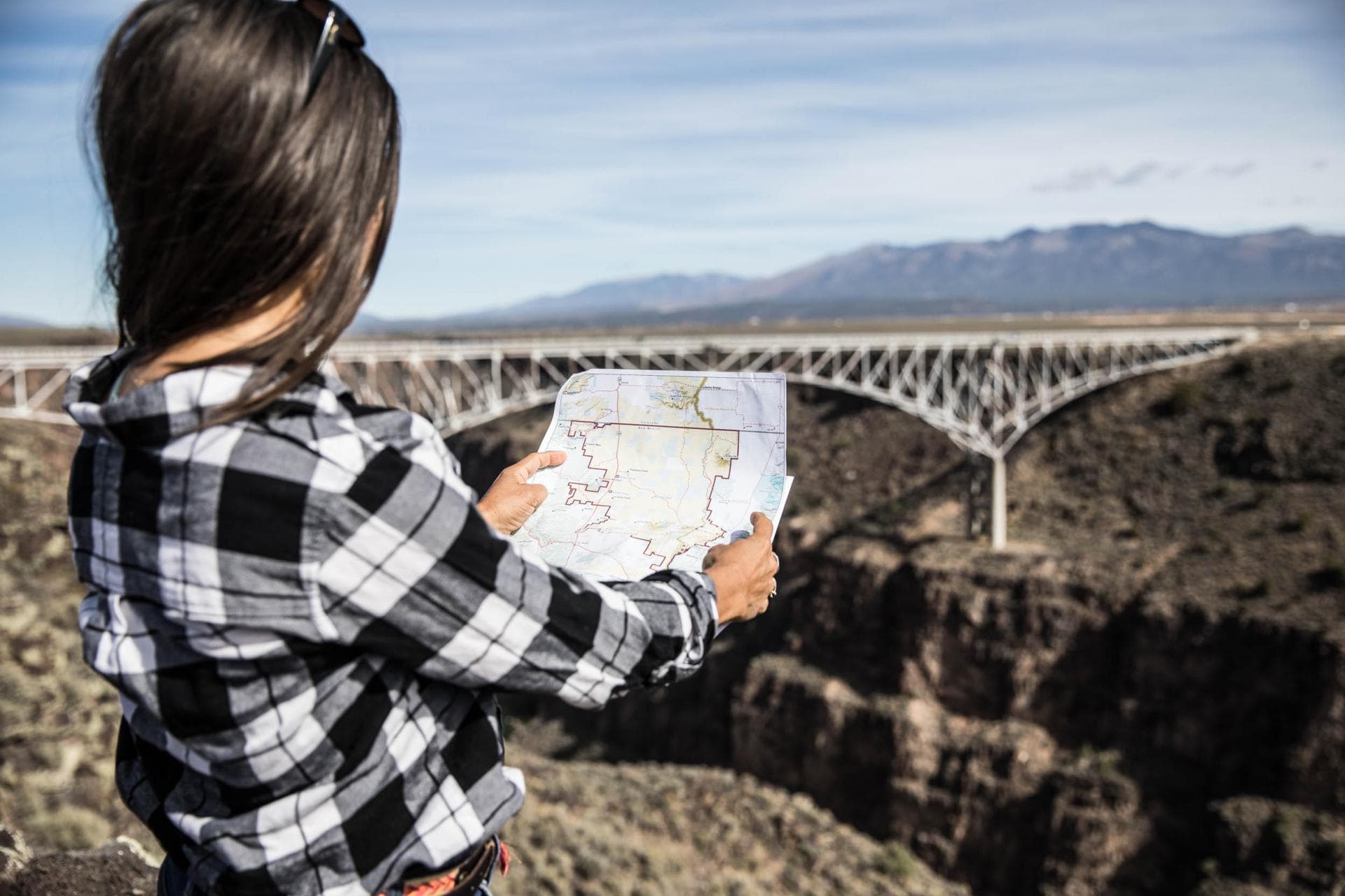 A woman holds a map as she looks at the Rio Grande Gorge and Bridge.